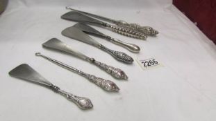 Five silver handles shoe horns and two silver handled button hooks.