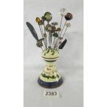 A Motto ware hat pin stand with 24 hat pins.