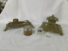 A heavy brass inkwell, a brass stand with candle snuffers and 2 ink wells.