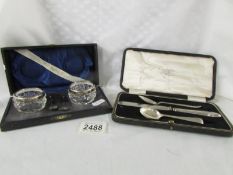 A cased pair of silver rimmed glass salts with spoons,