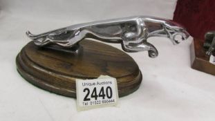 A Jaguar car mascot on oak base.