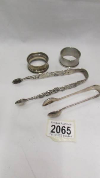 Two hall marked silver sugar tongs and two silver napkin rings.