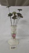 A floral decorated hat pin stand with 8 hat pins.