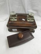 A wooden desk stand with two glass inkwells and a desk blotter.