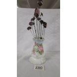 A rose decorated hat pin stand with 14 hat pins.