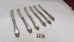 Six silver handled butter knives.