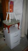 A two drawer file cabinet, 2 vintage stools and a tin musical house biscuit tin. (Collect only).