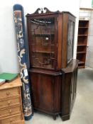 A dark wood stained corner cabinet with astragal glazed door.