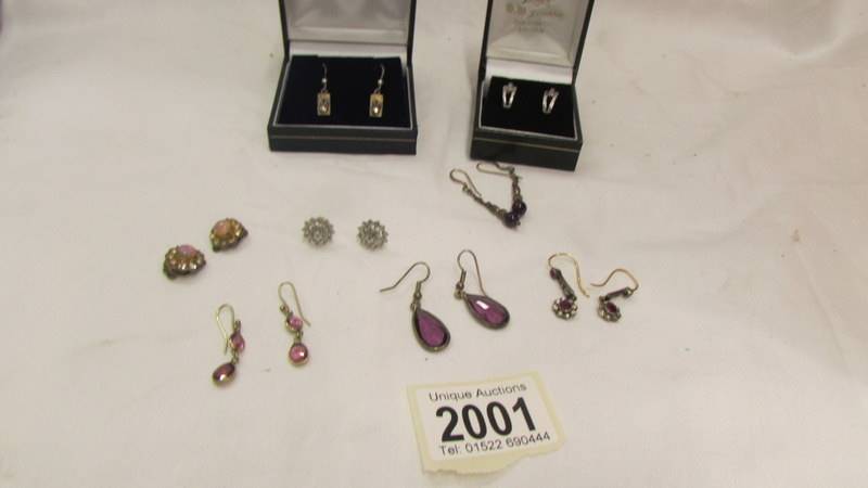 Two pairs of silver earrings and six other pairs of earrings.