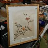 A framed and glazed embroidery of a bird.