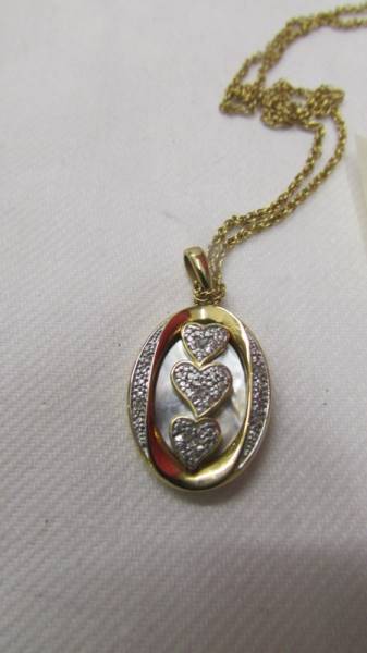 An unmarked pendant (tests as 9ct gold) fashioned as three hearts in an oval with seven small - Image 2 of 3