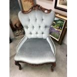 A Victorian style deep buttoned shield back nursing chair with carved mahogany frame