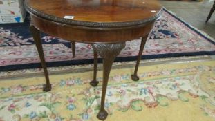 A mahogany demi lune table on ball and claw feet.