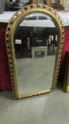 An arched top bevel edged mirror in gilt frame.