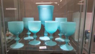 A large blue glass goblet and six smaller examples.