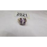 An amethyst set oblong ring with fancy textures gold shoulders and mount, set in 9ct gold, size O.