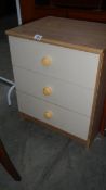 A three drawer bedside chest.