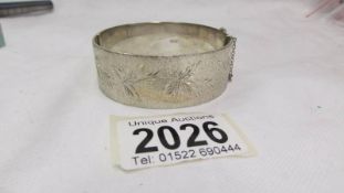 A good quality heavy silver bangle textured with trailing all round leaves, dated Birmingham 1974.