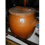 A large terracotta pot with wooden lid.