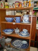 Four shelves of sundry items including blue and white china, mincers etc.