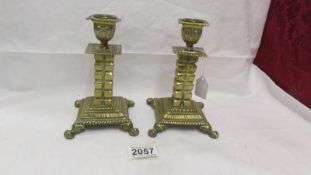 A pair of 19th century brass candlesticks on square footed bases with cubed columns.