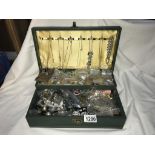 A green jewellery box with an assortment of costume jewellery