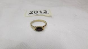 An oval set garnet ring in 9ct gold, size P half.