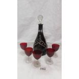 A red cut glass decanter with 5 red glasses.