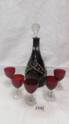 A red cut glass decanter with 5 red glasses.