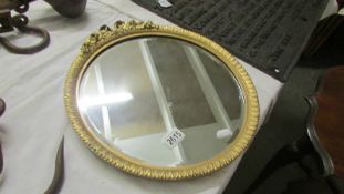 A circular gilt framed bevel edged mirror.