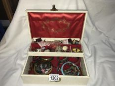 A white jewellery box with assorted bangles, bracelets,