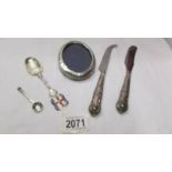 A silver handled cheese knife, a silver handled butter knife, an oval silver photo frame (a/f),