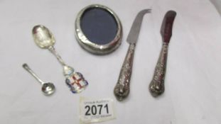 A silver handled cheese knife, a silver handled butter knife, an oval silver photo frame (a/f),