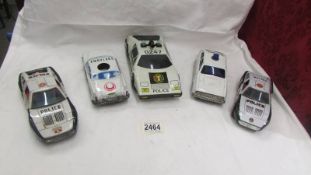 Three Japanese tin plate friction police cars, another police car and an ambulance.