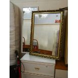 A gilt framed mirror and a white framed mirror.