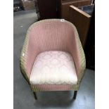 A pink Lloyd Loom chair with storage compartment