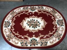 An oval red/cream floral pattern rug (170cm x 120cm)