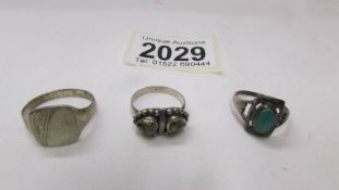 A silver signet ring and two other silver rings.