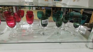 Seven cranberry glass stemmed glasses and eleven green examples.