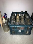 A plastic crate of vintage milk bottles and 2 soda syphons