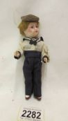 A small Victorian porcelain doll in a sailor suit, marked 301.