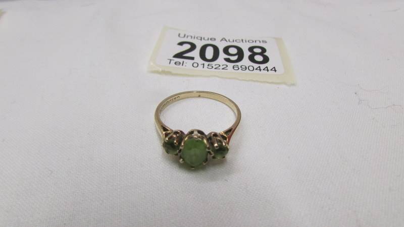 A 9ct gold ring set three peridot, size O half.