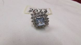 A cluster ring set with white stones and centre blue stone in white metal.