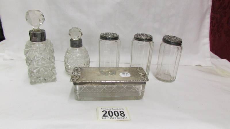 5 toilet bottles with silver tops and a glass trinket box with silver top.