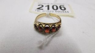 A yellow metal ring set red stones, size M half.
