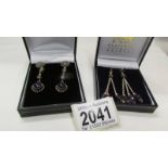 Two pairs of silver pendant earrings.