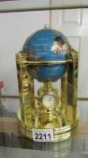 A gemstone globe weather station with clock and thermometer.