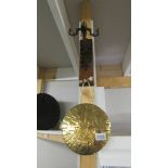 A brass dinner gong on wall mounting metal bracket.