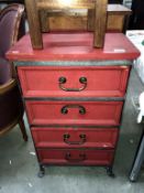 A red stained chest of drawers in an iron frame