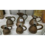 Six copper jugs in assorted sizes.